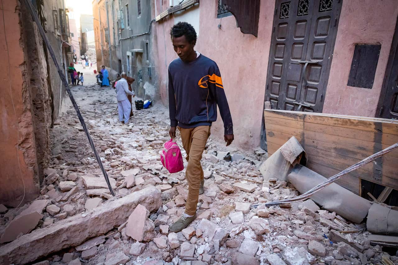A man walks through the rubble in an alleyway